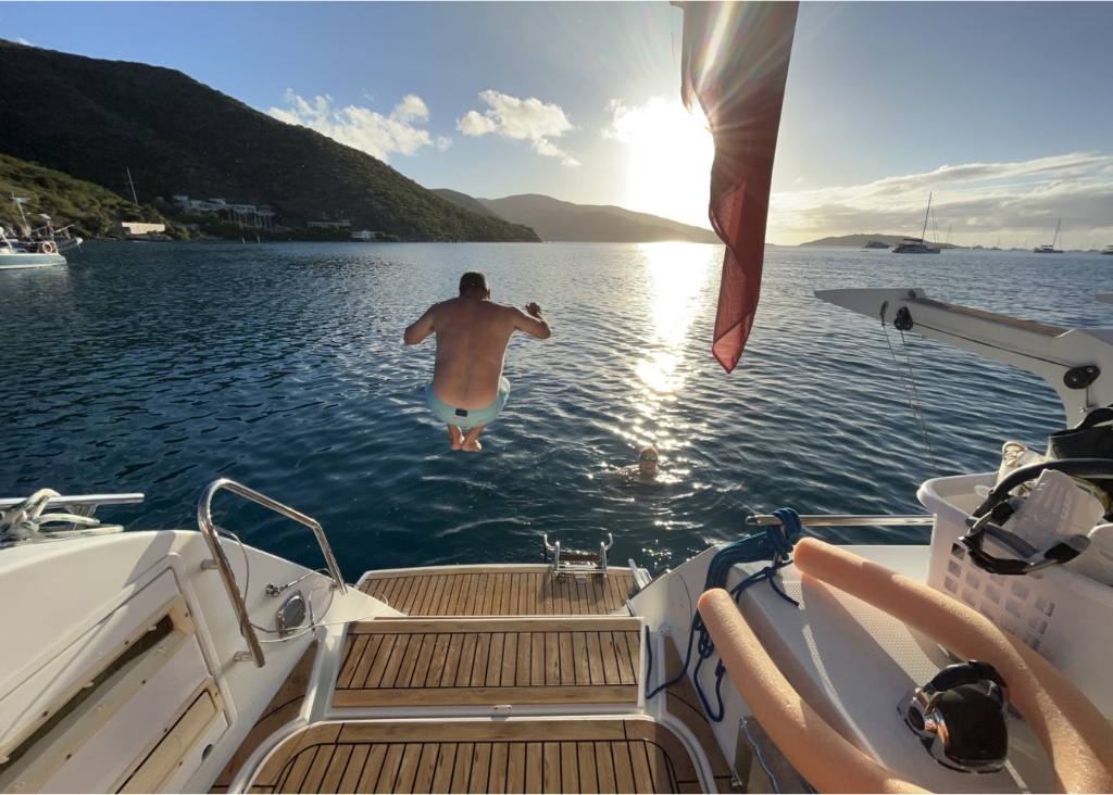 a man bombing off the back of yacht Sandy Cinco into the sea in a beautiful anchorage
